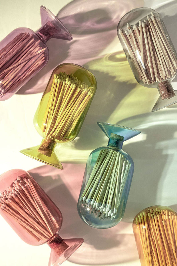 Colorful glass match holders with matches on a light background