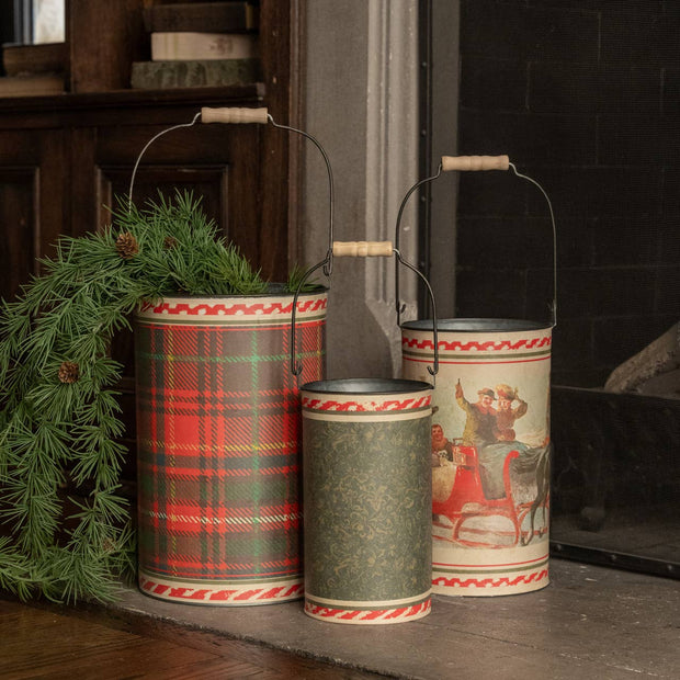 Three decorative metal buckets with plaid patterns and rustic designs on a wooden surface.