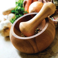 Wooden mortar and pestle with ingredients on a kitchen counter