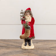 Decorative Christmas scene with a Santa figure, stockings, and a small tree.