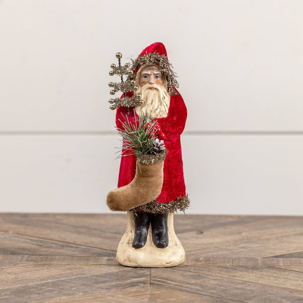Decorative Christmas scene with a Santa figure, stockings, and a small tree.