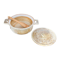 Small ceramic crock with wooden spoon and lid on a white background