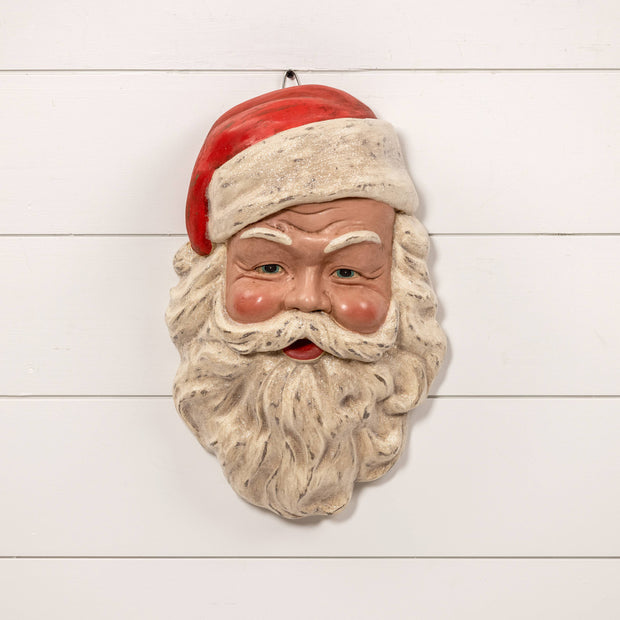 Decorative wall hanging of a Santa Claus face on a white wooden background