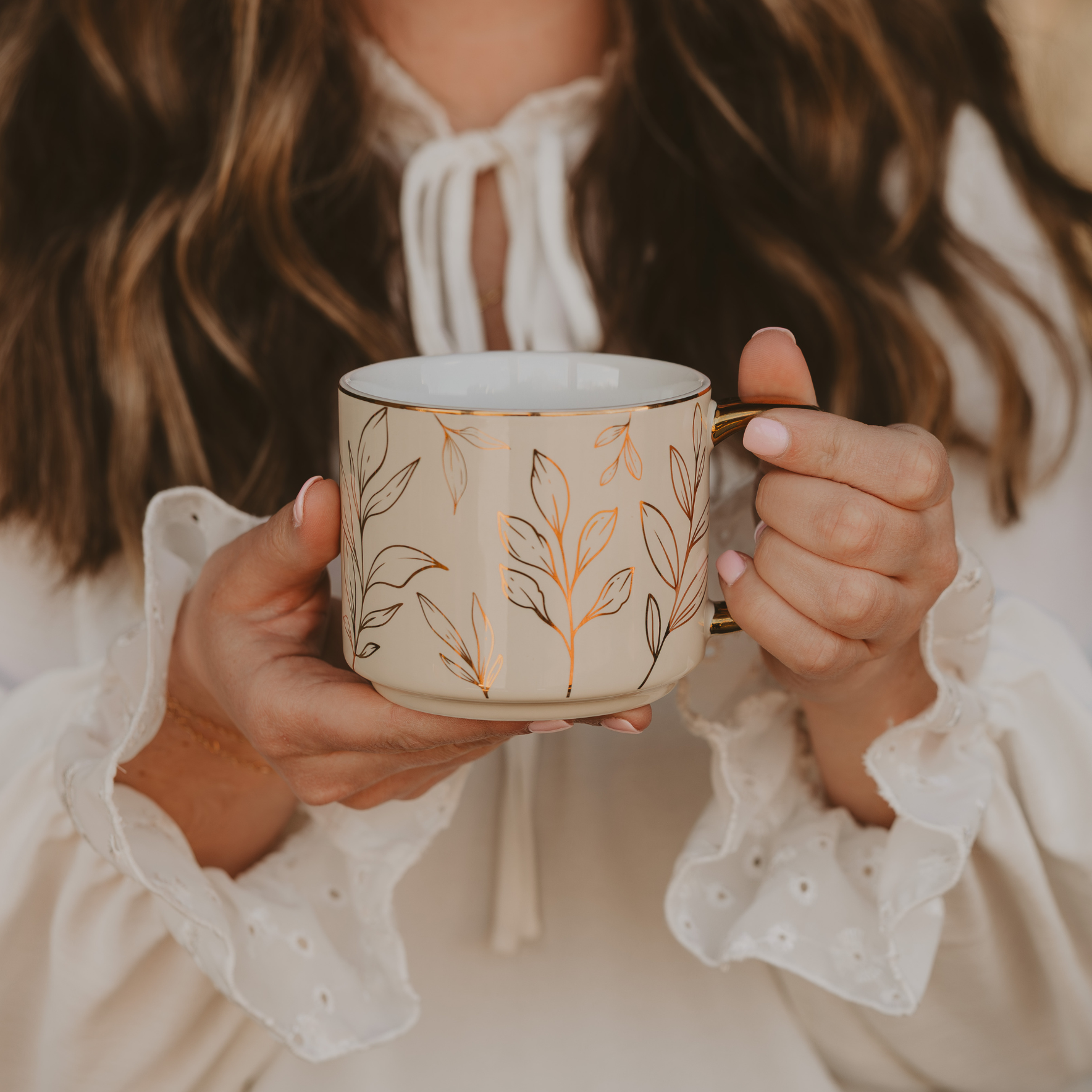 Person holding a decorative mug with floral patterns