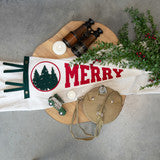 Decorative Christmas towel with 'Merry' text and festive design on a wooden surface.