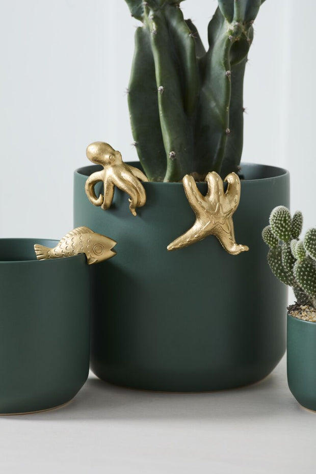 Three golden sea creatures hanging on a pot.