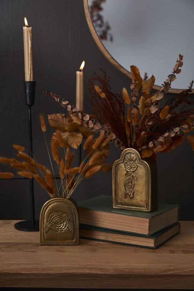 Decorative setup with candles, books, and dried plants on a wooden surface.