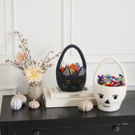 Decorative items on a shelf including a small dog figurine, a black cat-shaped bag, and a white skull with red eyes.