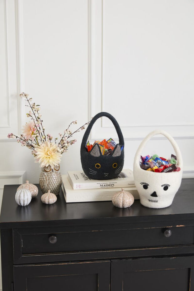 Decorative items on a shelf including a small dog figurine, a black cat-shaped bag, and a white skull with red eyes.