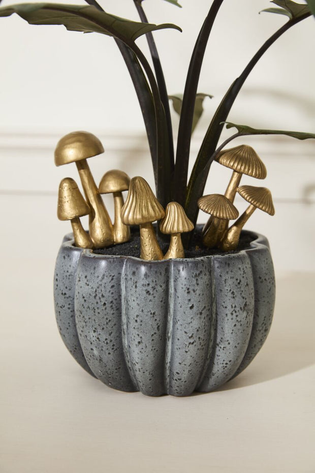 Decorative planter with gold mushrooms and green leaves on a neutral background